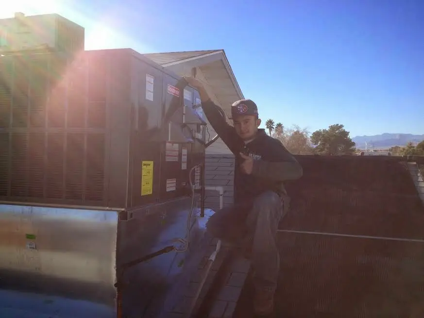 HVAC technician performing AC Tune-Up on a rooftop unit in Menominee